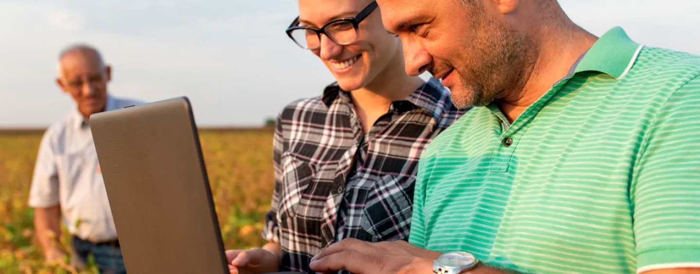 Man and woman looking at laptop in field courtesy of AdobeStock