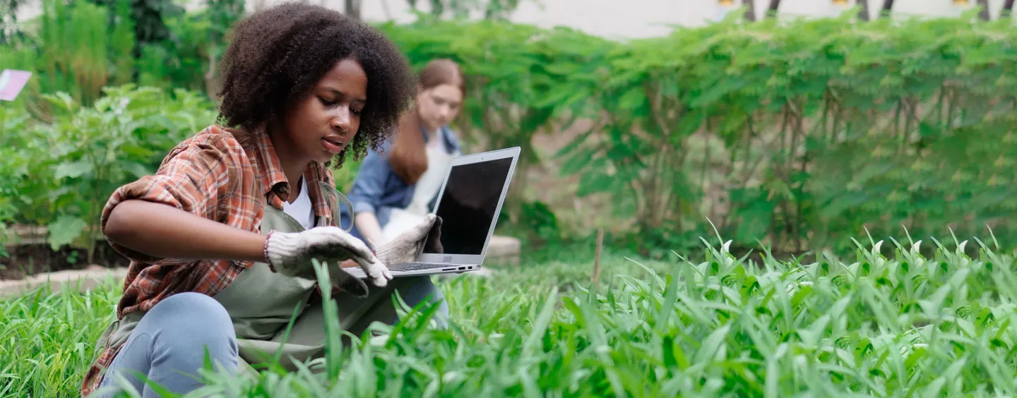 Girl working in field with laptop, courtesy of Adobe Stock