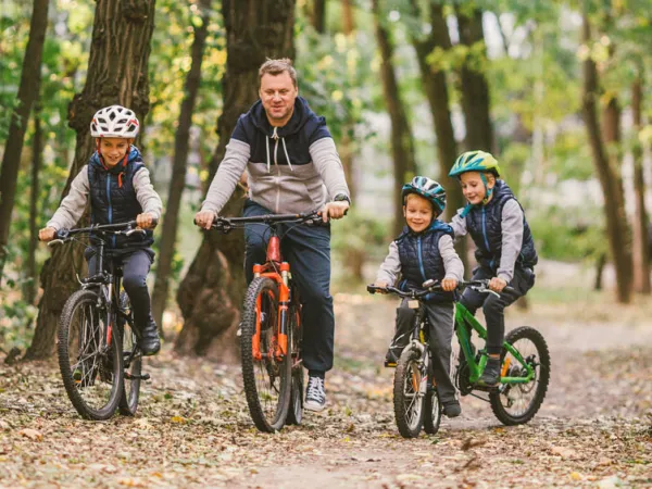 Family riding bikes in forest, courtesy of Adobe Stock