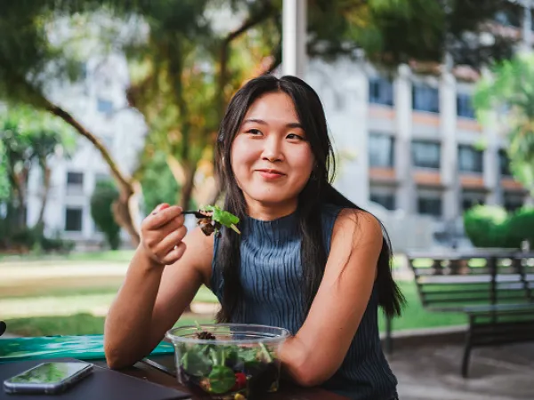 College student eating a salad on campus. Image courtesy of Adobe Stock. 