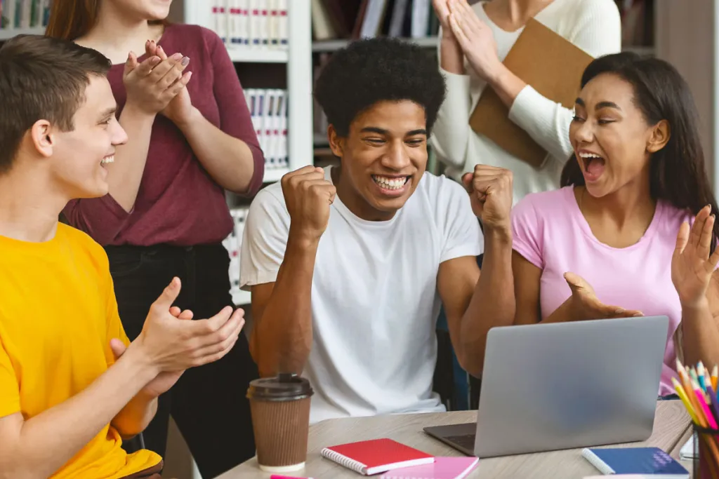 group of people cheering for student at laptop, courtesy of Adobe Stock