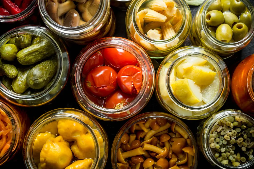 Photo of fruits, vegetables, and mushrooms preserved in jars. Courtesy of Adobe Stock.