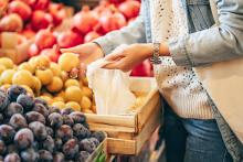 Shopper puts fruits and vegetables in cotton produce bag at food market. Image courtesy of Adobe Stock. 
