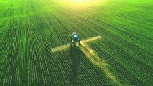 Aerial view of tractor spraying crop field. Image courtesy of Adobe Stock. 