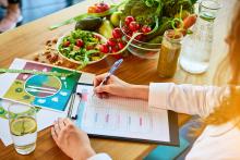 Dietician writing nutrition plan with fruits, vegetables, and health drinks