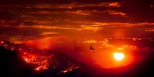 Wildfire burning at sunset with helicopter in foreground