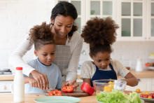 Mother and children cooking vegetables together. Image courtesy of Adobe Stock. 